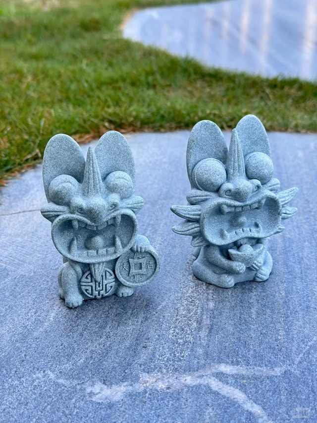 Two small unglazed grey clay cats side by side