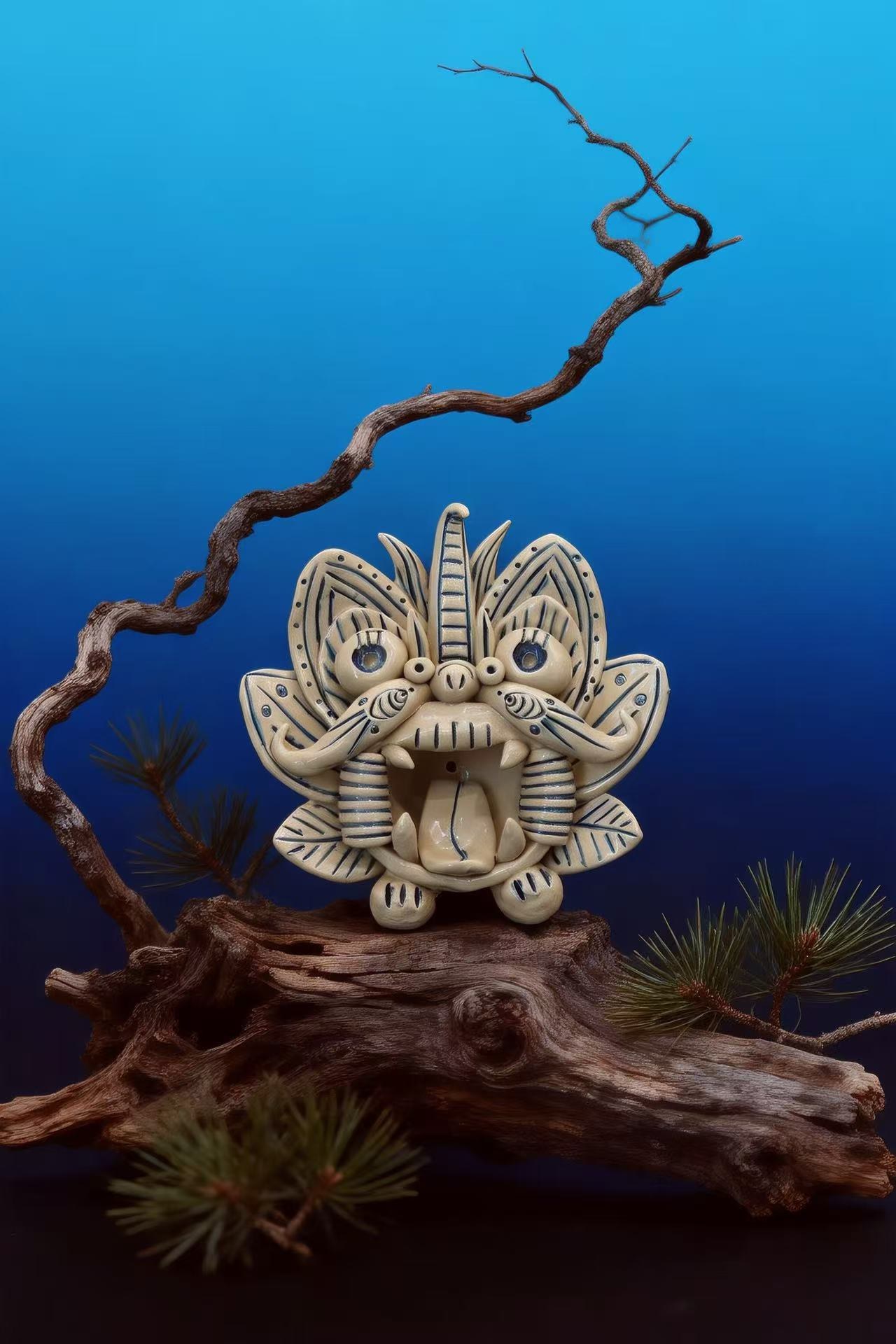Cangyan ceramic guardian, cream glaze with cobalt lines and a horn, on driftwood against a deep blue backdrop