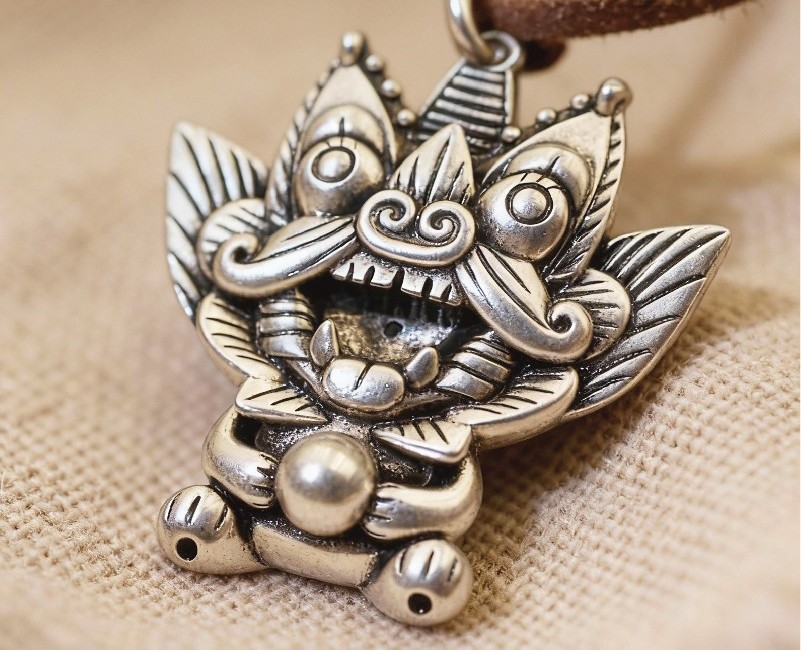 Jinxi silver pendant, a round-eyed roof cat holding a gold orb in its paws, on burlap