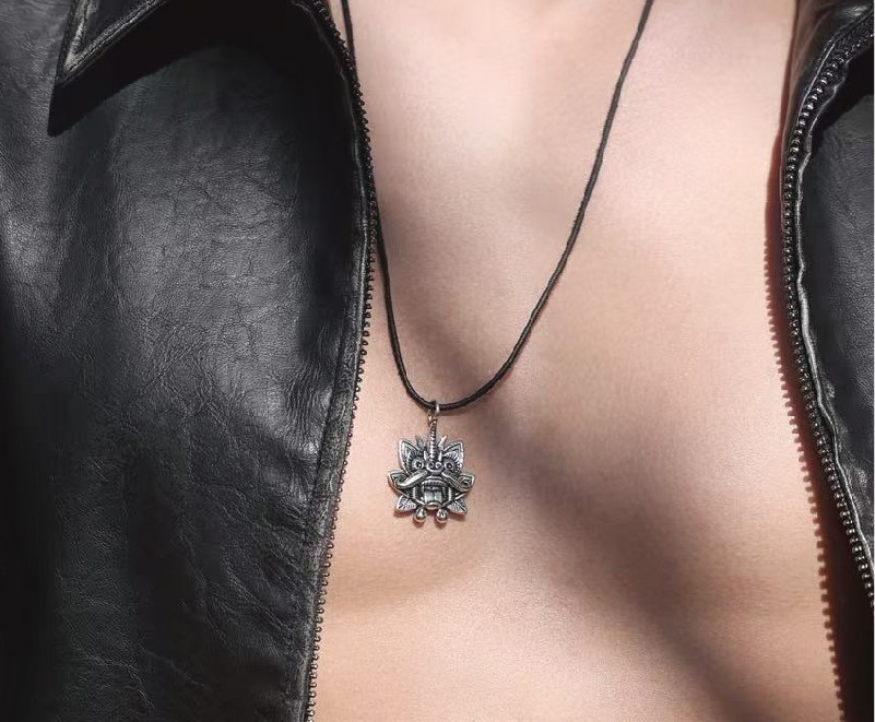 The Cangyan pendant worn on a black cord over an open leather jacket